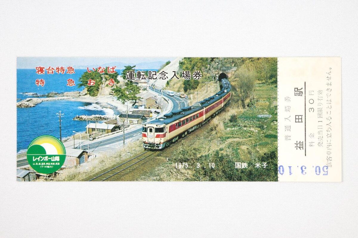入場券の表面。山陰の海岸沿いを走る特急列車の写真に、寝台特急「いなば」特急「おき」運転記念入場券の文字が置かれている。サイズは15.8 × 6.1 cm。