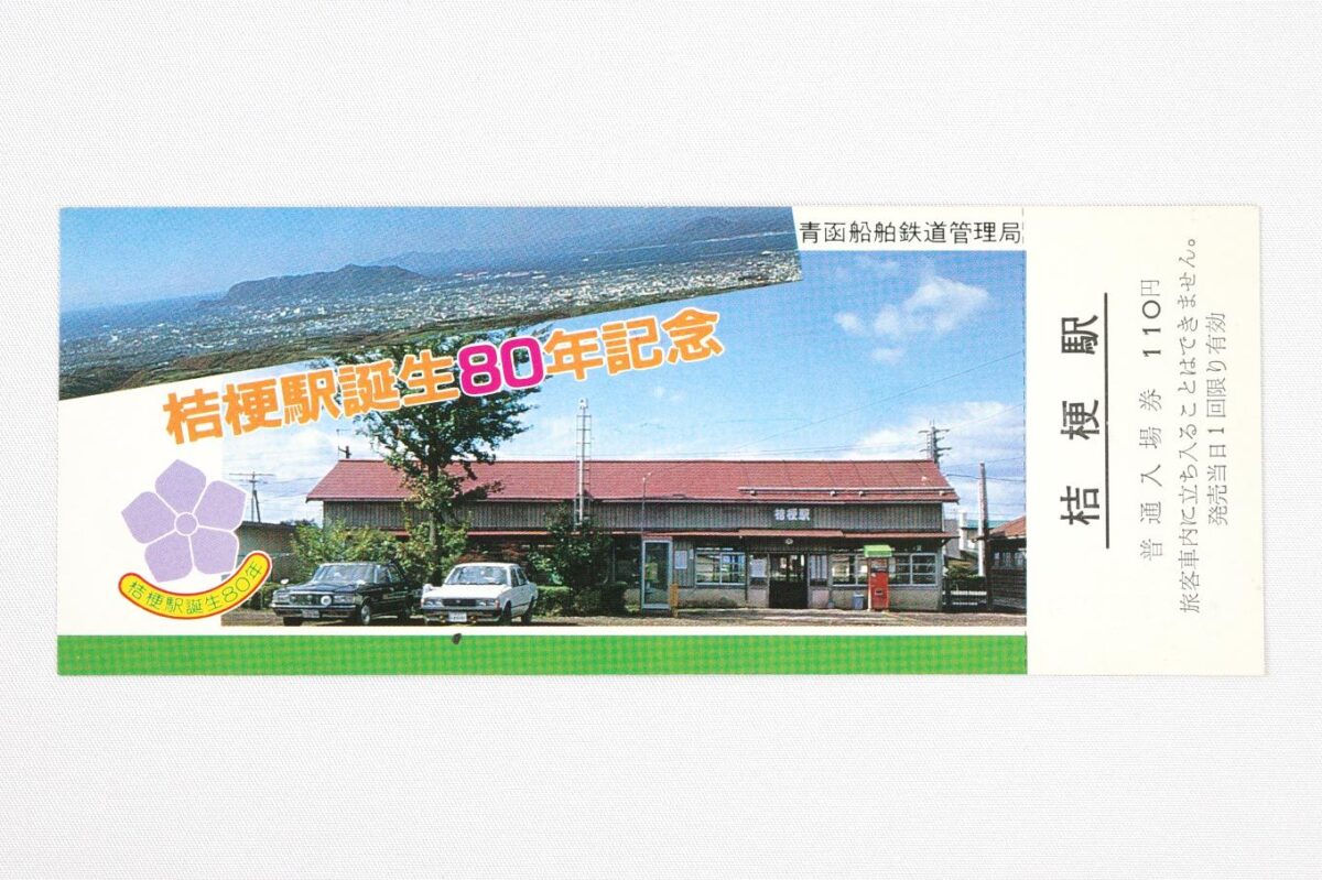 入場券の表面。桔梗駅の木造駅舎の写真を大きく置き、その左上部分に重ねるように周辺の高台から眺めた函館市街と函館山の写真に、桔梗駅誕生80年記念の文字が置かれている。サイズは15.5 × 6cm。