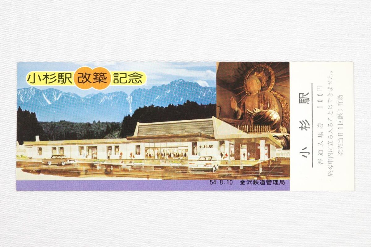 入場券の表面。上部には立山連峰の劔岳と小杉大仏の写真が並べられ、写真の上に小杉駅改築記念の文字が置かれている。下部には新駅舎のイラストが配されている。サイズは15.4 × 5.9 cm。