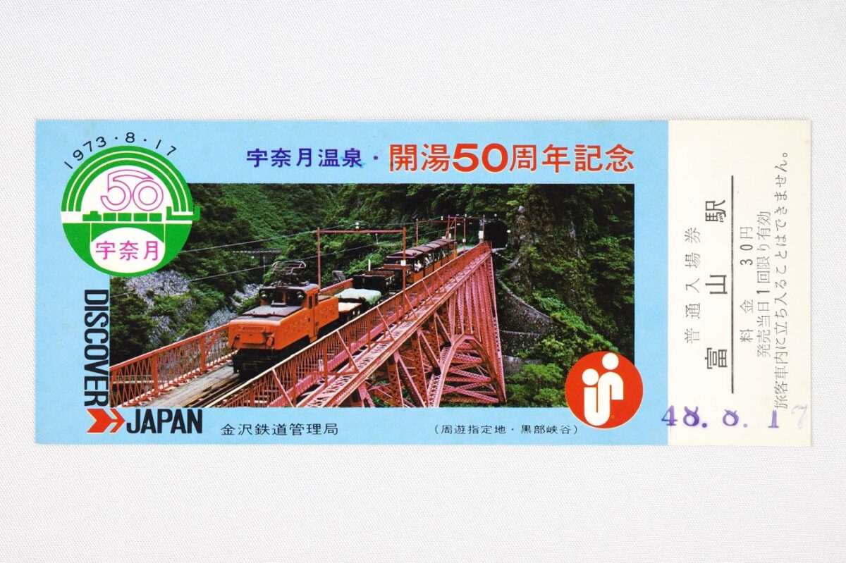 入場券の表面。赤いアーチ鉄橋を渡る、黒部渓谷鉄道の列車の写真が大きく配置され、周囲を宇奈月温泉や開湯50周年のほか金沢鉄道管理局やDISCOVER JAPANなどの文字が取り巻いている。サイズは14.7×6.2cm。